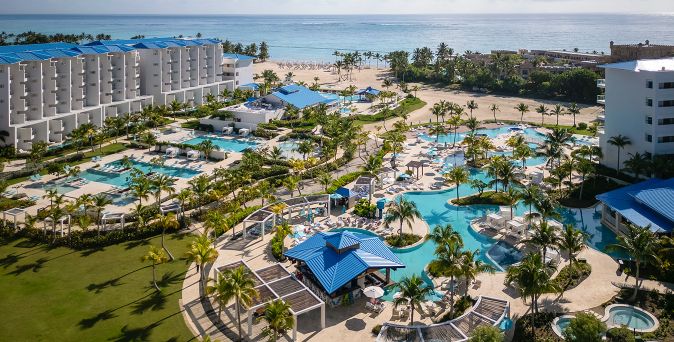 Luftaufnahme eines großen Resorts in Punta Cana mit mehreren Pools, Palmen, Liegen und direktem Zugang zum Strand und Meer
