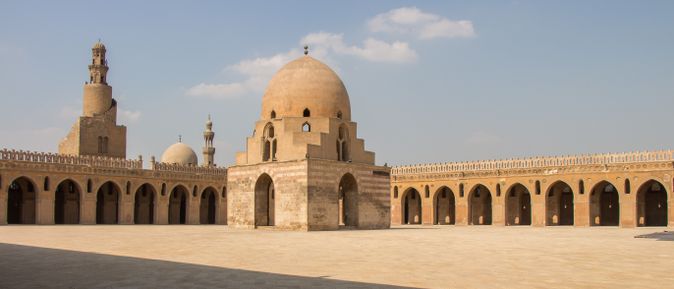 Innenhof der Ibn-Tulun-Moschee mit zentraler Kuppel und umlaufenden Arkaden unter blauem Himmel