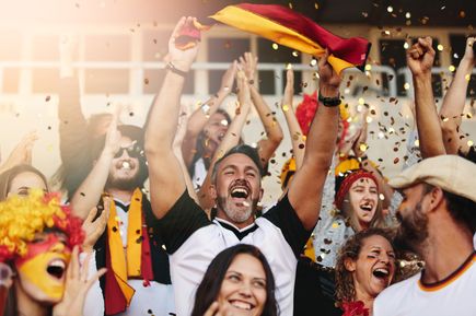 Gruppe jubelnder Deutschland-Fans mit erhobenen Armen und Konfetti in der Luft