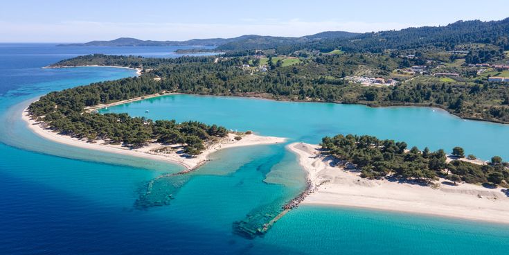 Luftaufnahme einer Küstenlandschaft Glarokavos Beach mit türkisfarbenem Wasser, Sandstränden und bewaldeten Hügeln im Hintergrund.