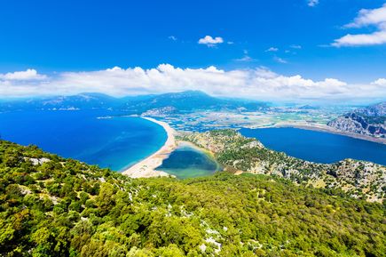 Panoramablick auf den Iztuzu Beach mit schmaler Landzunge zwischen Meer und Lagune, umgeben von grüner Hügellandschaft