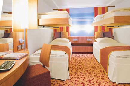 Innenkabine auf der AIDAsol mit zwei unteren Betten und zwei oberen Klappbetten, warmen Farben, modernem Mobiliar und einem Schreibtischbereich