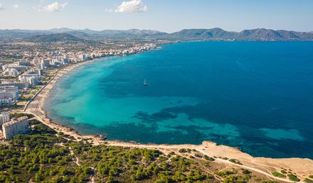 Panorama von Cala Millor auf Mallorca mit langem Sandstrand, türkisblauem Wasser und Hotelanlagen entlang der Küste