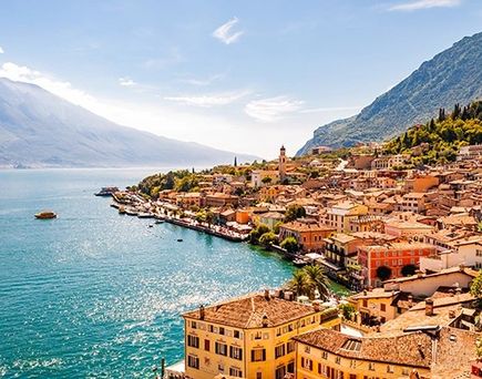 Küste mit felsigen Klippen und türkisfarbenem Meer in Albanien, im Hintergrund Berge und bewölkter Himmel