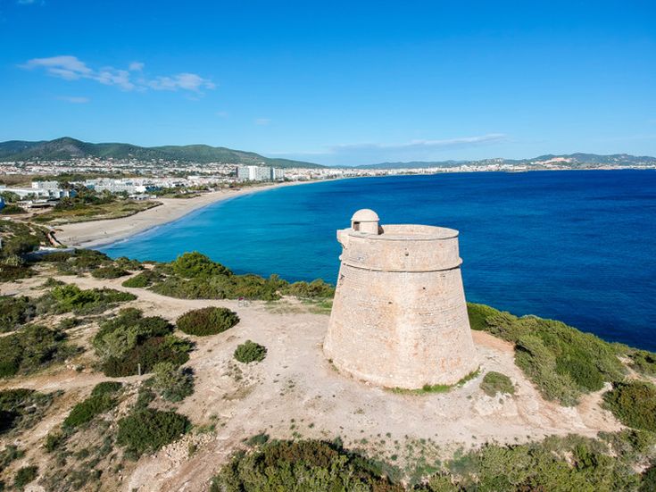 Runder, historischer Wachturm auf einer Anhöhe mit Blick auf die Küste und das Meer von Playa d'en Bossa auf Ibiza
