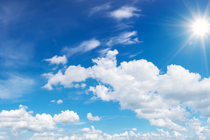 Blauer Himmel mit weißen Wolken und Sonne oben rechts in der Ecke.