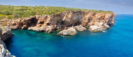 Steilküste bei S’Algar auf Menorca mit felsigen Klippen, Höhlen und türkisblauem Meer