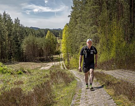 Joey Kelly wandert auf einem befestigten Weg durch eine waldreiche Mittelgebirgslandschaft
