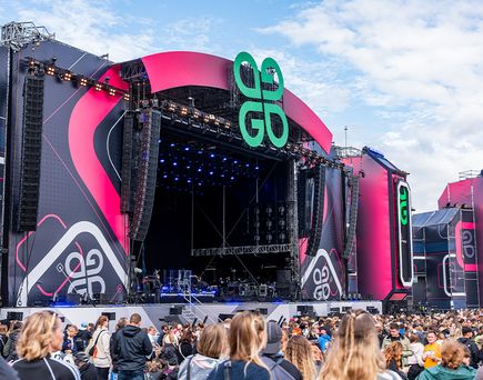 Große Open-Air-Bühne bei Tageslicht mit GG-Logo und Technikaufbau vor zahlreichem Publikum beim Glücksgefühle Festival