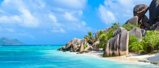 Granitfelsen, Palmen und türkisfarbenes Meer am Strand Anse Source d’Argent auf La Digue auf den Seychellen