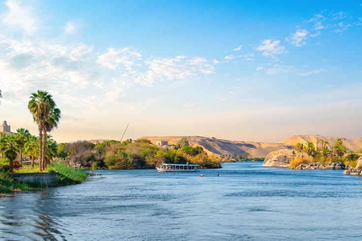 Traditionelles Boot auf dem Nil zwischen Palmen, Felsen und blauem Flusslauf