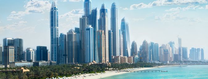 Skyline von Dubai mit hohen Wolkenkratzern am Meer unter blauem Himmel