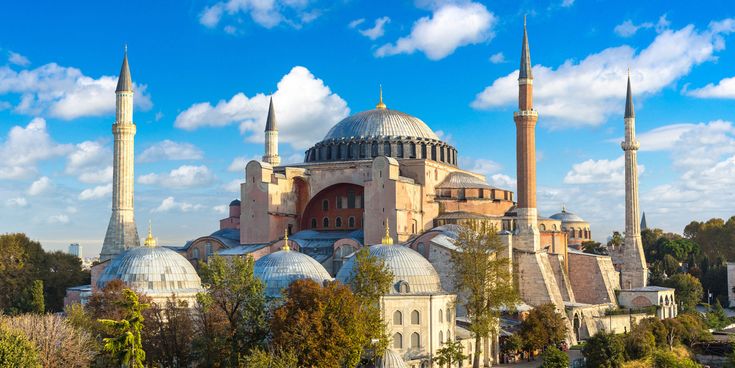 Hagia Sophia in Istanbul mit großer Hauptkuppel und Minaretten, umgeben von Bäumen bei klarem Himmel