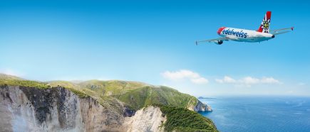 Edelweiss‑Air Airbus A320 überfliegt die Küstenlandschaft von Zakynthos mit steilen Klippen, grünen Hügeln und tiefblauem Meer unter klarem Himmel