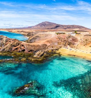 Blick auf eine felsige Küste am glasklaren, blauen Meer