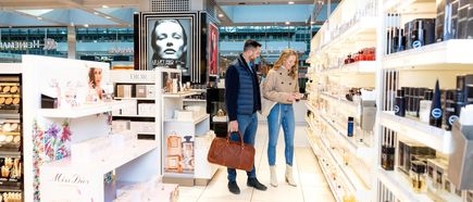 Reisende stöbern im Duty-Free-Shop am Flughafen Hamburg und betrachten Parfüms sowie Kosmetikprodukte bekannter Marken