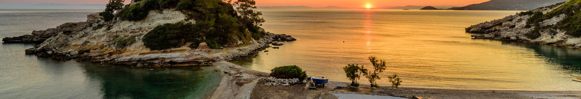 Sonnenuntergang über einer kleinen Insel mit Bäumen und einem Steg im ruhigen Wasser.