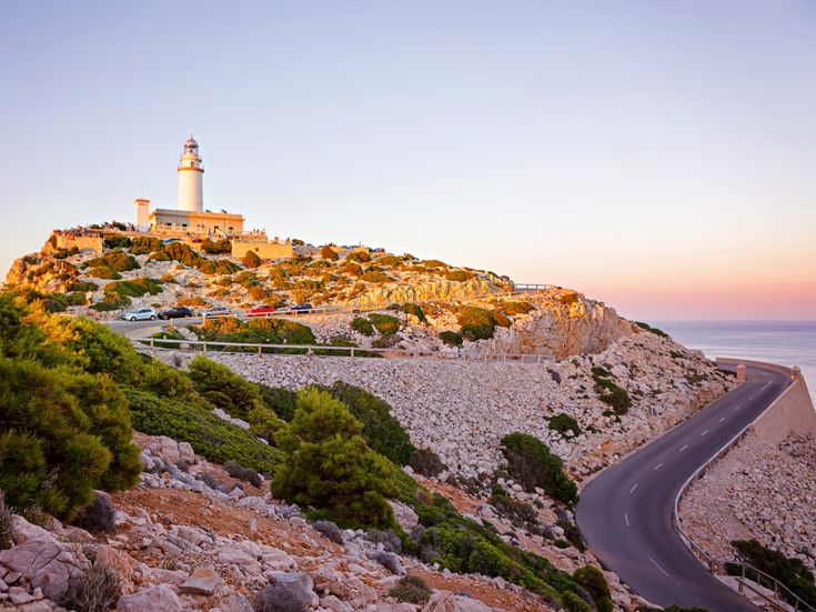 Sonnenuntergang am Leuchtturm Cap de Formentor auf Mallorca mit Panoramastraße und felsiger Landschaft