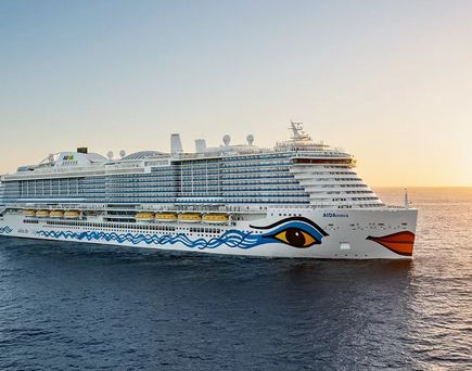 Kreuzfahrtschiff AIDA mit markantem Augen- und Lippenmotiv am Bug fährt bei Sonnenuntergang auf dem Meer
