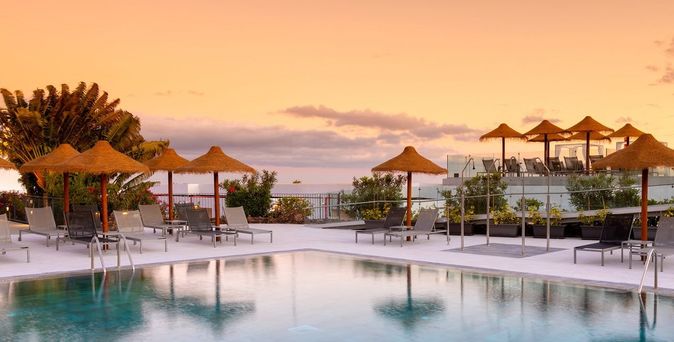 Poolbereich mit Liegestühlen und Strohdach-Sonnenschirmen bei Sonnenuntergang, Hotel SolMelia