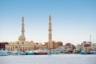 Aldahaar Moschee in Ägypten mit zwei hohen Minaretten am Ufer, davor zahlreiche Boote und Yachten im Wasser