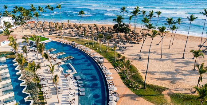 Luftaufnahme des Secrets Tides Punta Cana mit geschwungenem Pool, Sonnenliegen, Palmenstrand und direkter Lage am türkisblauen Meer in Punta Cana, Dominikanische Republik