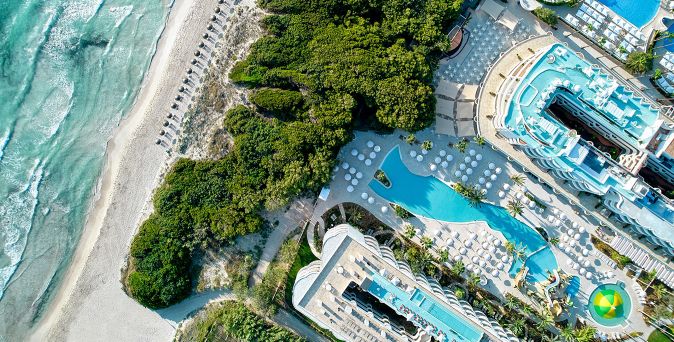 Luftaufnahme des Iberostar Selection Albufera Park mit großem Pool, direktem Zugang zum weißen Sandstrand und dichter grüner Vegetation auf Mallorca