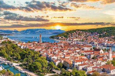 Altstadt von Trogir in Kroatien mit roten Ziegeldächern, historischem Kirchturm, Hafen und Panorama bei Sonnenuntergang über der Adria