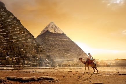 Reiter auf einem Kamel vor den Pyramiden von Gizeh bei Sonnenuntergang