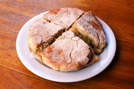 Bolo do Caco, traditionelles Fladenbrot von Madeira, in Stücke geschnitten auf einem weißen Teller auf einem Holztisch