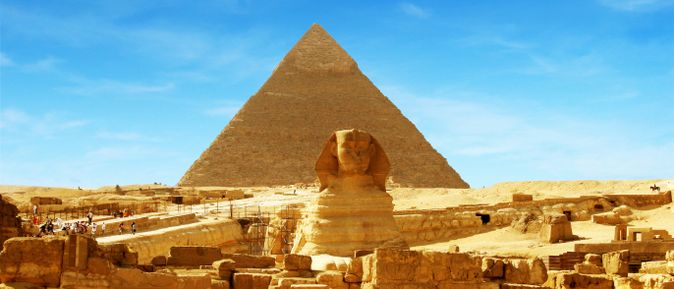 Die Große Sphinx von Gizeh vor der Cheops-Pyramide in der Wüste bei blauem Himmel