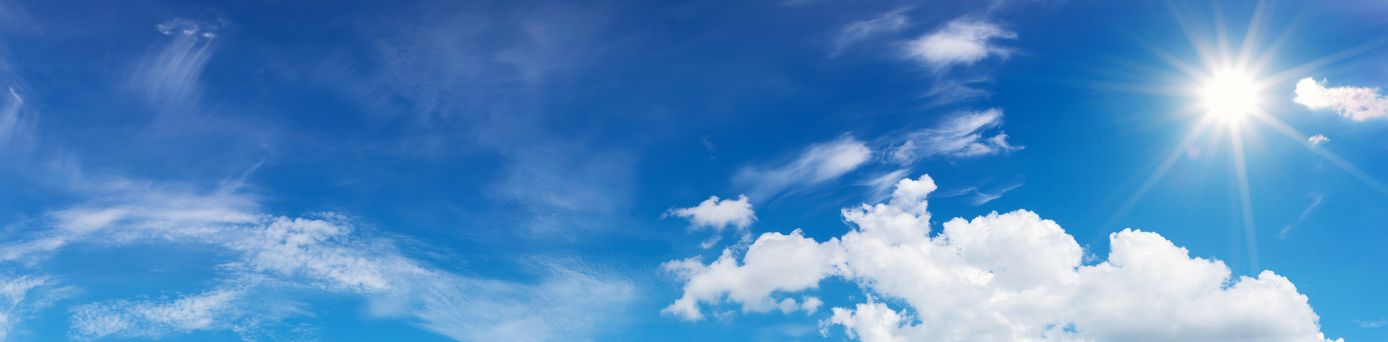 Blauer Himmel mit vereinzelten weißen Wolken und Sonnenlicht