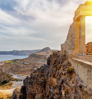 Antike Säulenruine auf einem Felsen mit Blick auf Küste und Meer bei Sonnenuntergang auf Rhodos