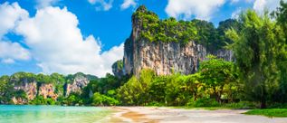 Strand von Railay Beach in Thailand mit markanten Kalksteinfelsen, tropischer Vegetation und ruhigem Meer