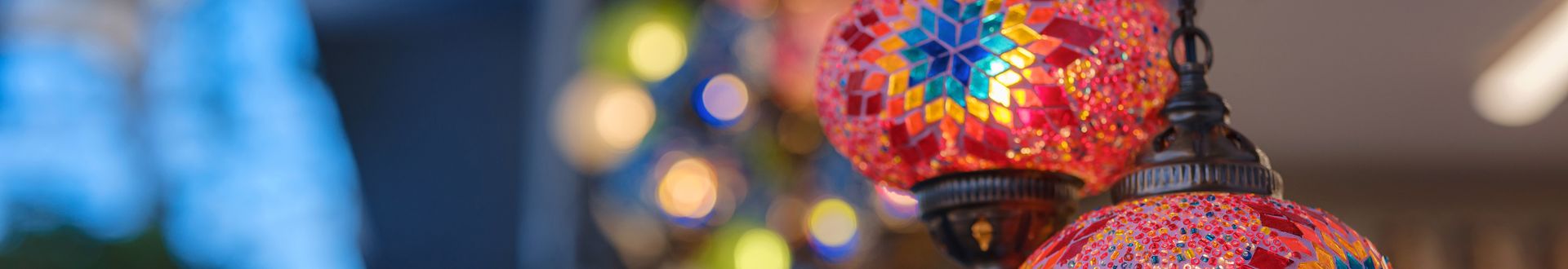 Nahaufnahme bunter orientalischer Mosaik-Laternen mit leuchtenden Mustern in Rot, Blau und Gold, die an einer Kette hängen