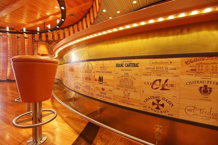 Die Vinothek auf der AIDAsol mit einer geschwungenen Bar, warmen Holzelementen und dekorativen Weinetiketten an der Frontverkleidung