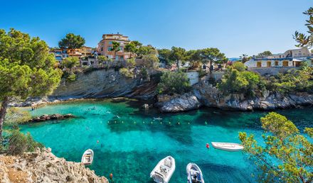 Cala Fornells auf Mallorca mit kristallklarem Wasser, kleinen Booten, Badebucht und Häusern entlang der felsigen Mittelmeerküste