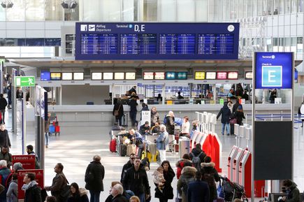 Check-in-Bereich im Terminal 2 des Flughafens Frankfurt mit Abfluganzeige, Schaltern und wartenden Reisenden