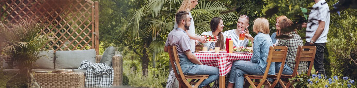 Gruppe von sechs Personen sitzt um einen Gartentisch