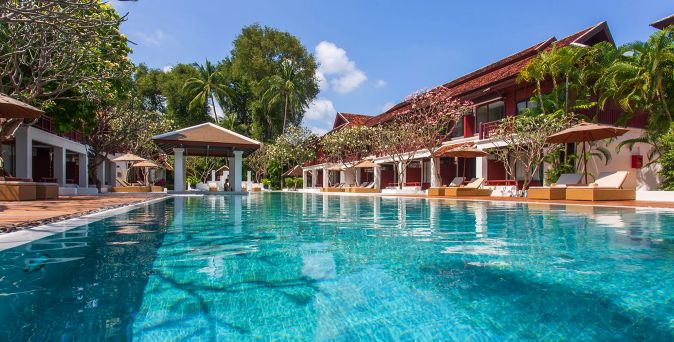 Poolbereich im Chaweng Regent Beach Resort auf Koh Samui mit klarem türkisfarbenem Wasser, umgeben von tropischen Pflanzen, Sonnenliegen und traditionellen Gebäuden in ruhiger Gartenanlage
