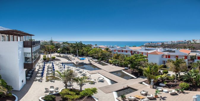 Frau mit Strohhut am Strand vor blauem Meer
