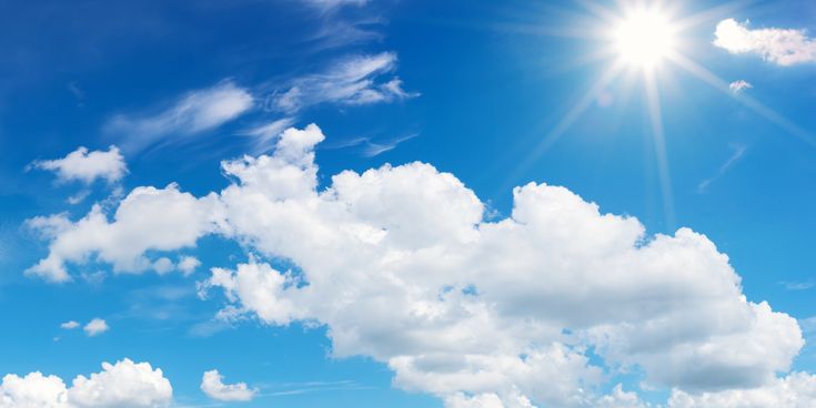 Blauer Himmel mit strahlender Sonne und weißen Wolken an einem Sommertag