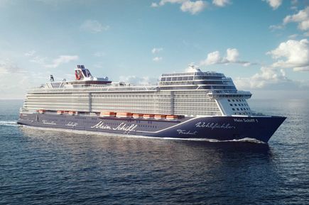 Das Kreuzfahrtschiff Mein Schiff 1 fährt bei blauem Himmel über das Meer und ist seitlich von vorn zu sehen.