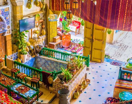 Innenhof eines traditionellen tunesischen Hauses mit bunten Fliesen, hölzernen Möbeln und dekorativen Lampen