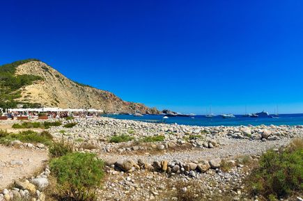 Strand Cala Jondal mit weißen Kieseln, Strandbars und Yachten im Meer