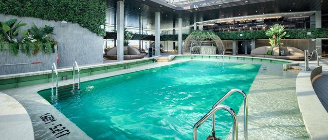 Botanic Garden Pool der MSC World America mit begrüntem Wanddekor, modernem Indoor-Poolbereich und Loungeflächen