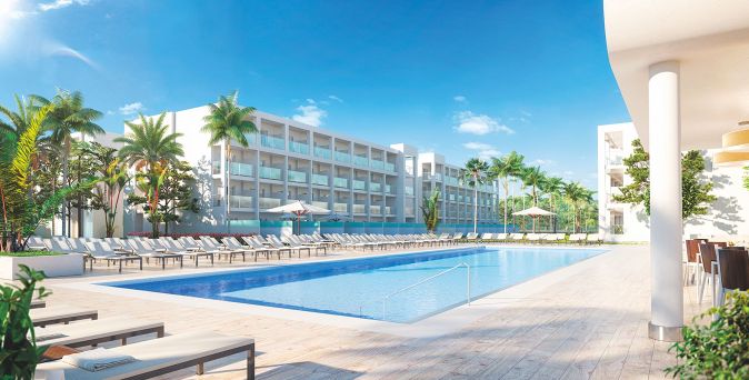 Großer rechteckiger Pool mit Liegen und Sonnenschirmen vor einem mehrstöckigen Hotelgebäude mit Balkonen und Palmen im Außenbereich des RIU Palace Phuket