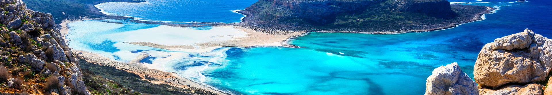 Panoramablick auf die Balos-Bucht auf Kreta mit türkisblauem Wasser, Sandstränden und felsigen Hügeln im Vordergrund.