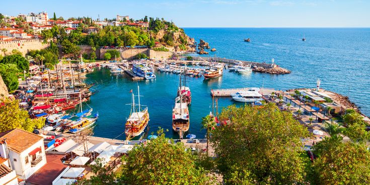 Hafen von Kaleiçi in Antalya, Türkei, mit vielen Booten, Altstadt-Häusern auf den Klippen und Blick auf das Mittelmeer