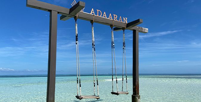 Frau mit Strohhut am Strand vor blauem Meer